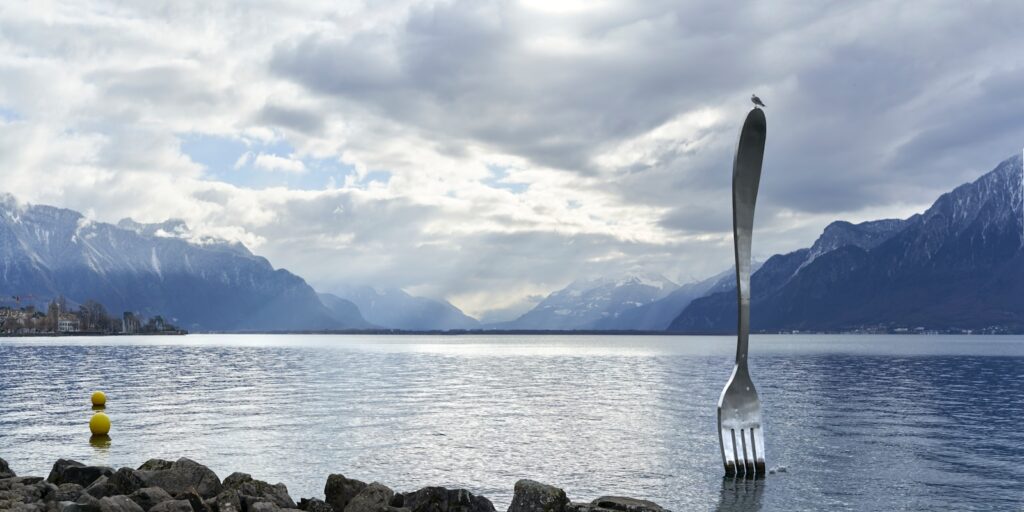 A fork sticking out of the water with mountains in the background